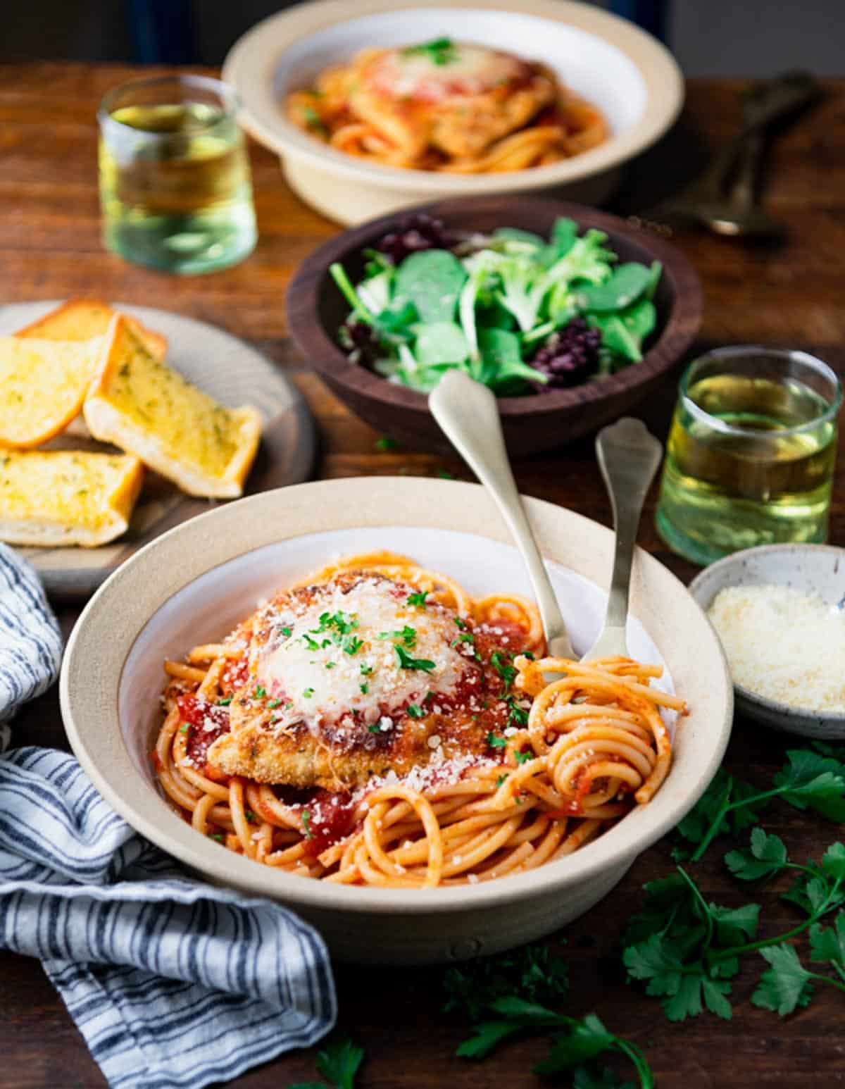 Two bowls of easy chicken parmesan recipe served on top of spaghetti with marinara.