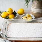 Pan of old fashioned lemon squares dusted with powdered sugar in a glass baking dish.