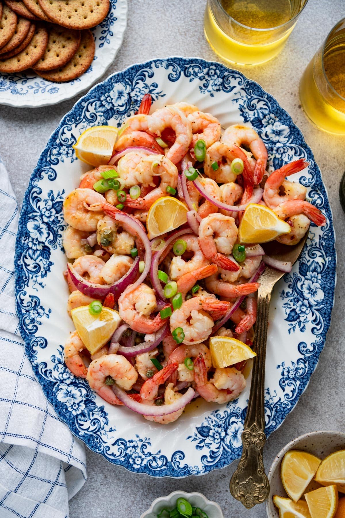 Overhead shot of a tray of easy pickled shrimp with fresh lemon wedges and red onions.