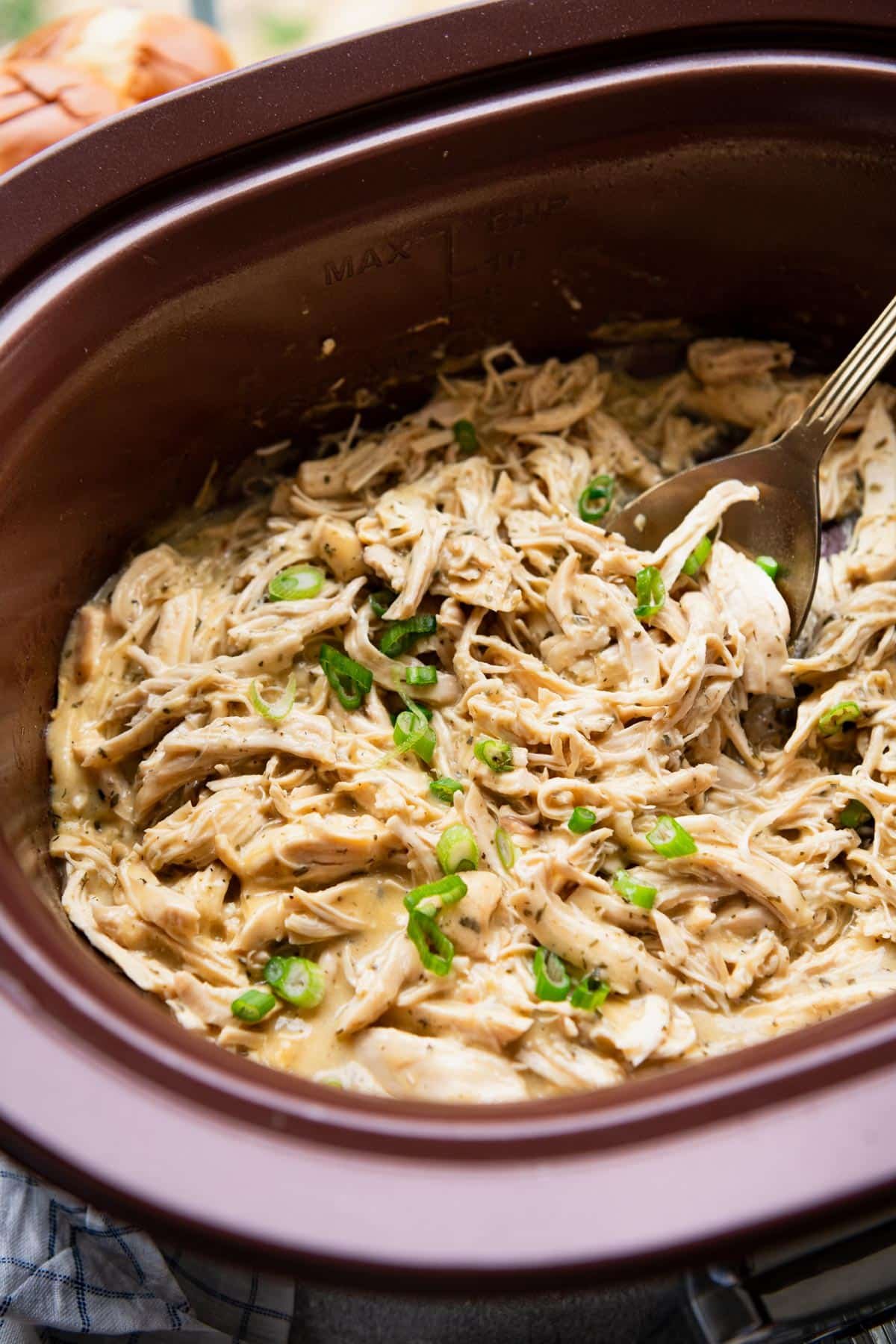 Close up side shot of ranch chicken crock pot recipe garnished with sliced green onions.