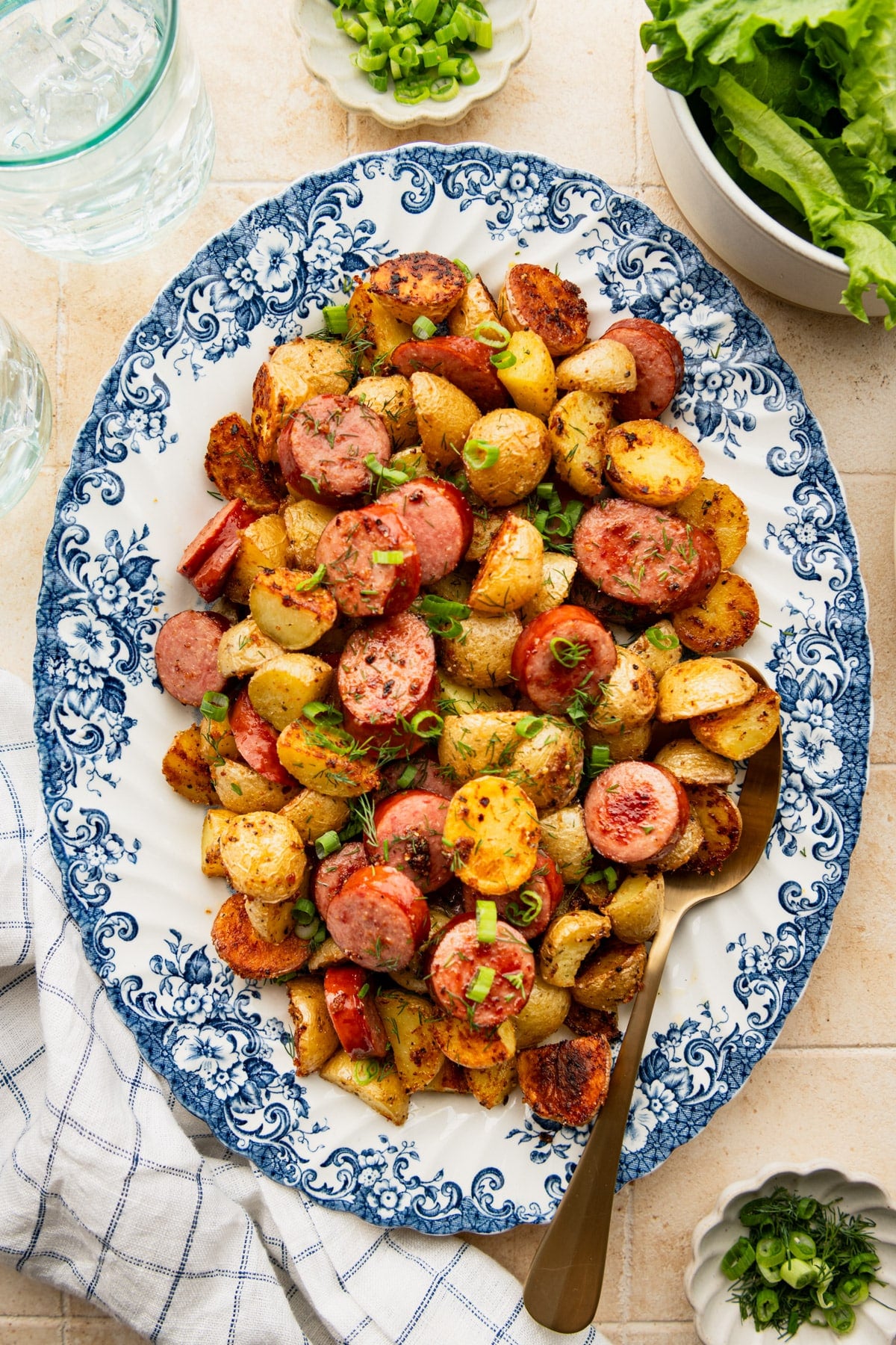 Overhead image of sheet pan sausage and potatoes on a blue and white tray.