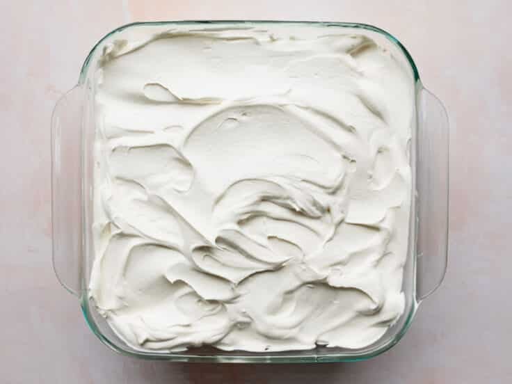 Spreading the whipped topping over the top of the icebox cake.