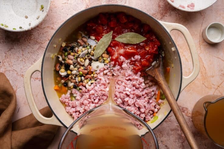 Stirring ham, beans, tomatoes, and seasoning to the pot.