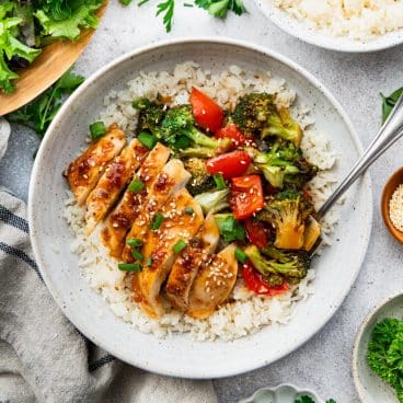 Square overhead image of baked teriyaki chicken in a bowl with rice.