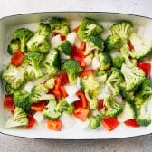 Broccoli, peppers, and onions in a white baking dish.