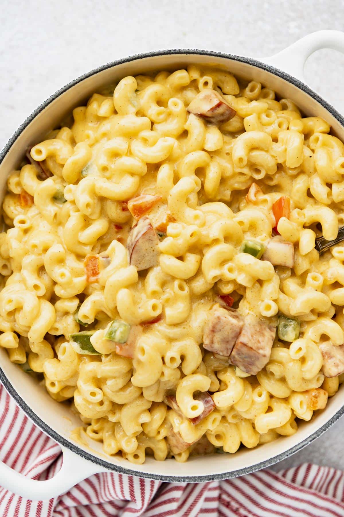 Close overhead image of creamy Cajun mac and cheese in a white Dutch oven.