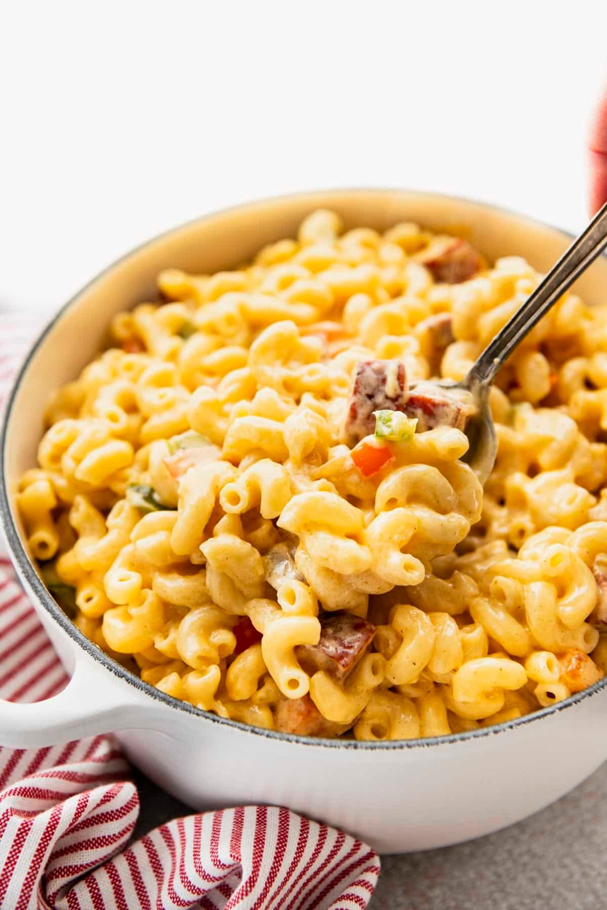Serving spoon in a big pot of creamy cajun mac and cheese.