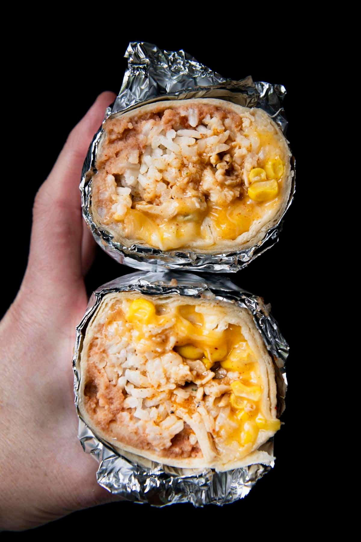 The best chicken burrito recipe in foil in front of a black background.