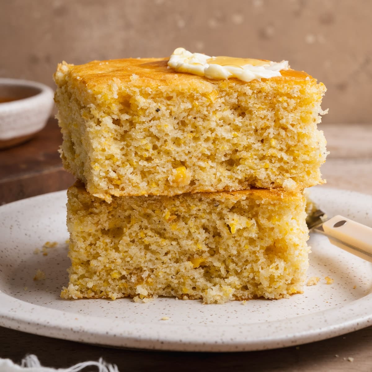 Two slices of homemade cornbread with corn stacked on a plate.