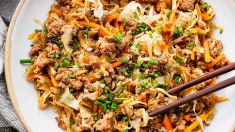 Close overhead shot of egg roll in a bowl with chopsticks.