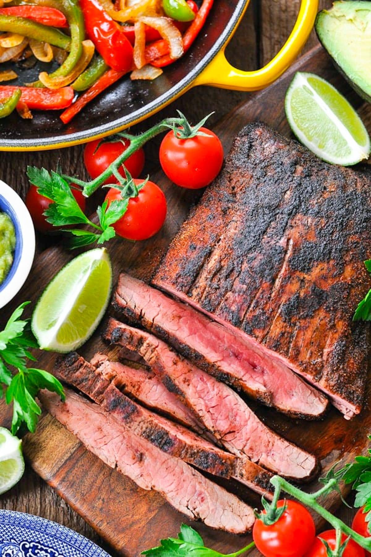 Overhead shot of grilled flank steak on a wooden cutting board for the best steak fajitas recipe.