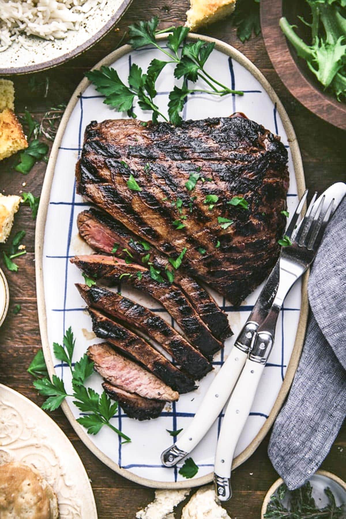 Overhead image of sliced grilled flank steak on a wooden table.