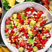 Overhead image of a bowl of fresh tomato, corn, and avocado salad.