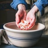 Hands adding imitation crab to a bowl of the best seafood salad recipe.