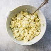 Process shot showing how to make a classic southern potato salad recipe in a white bowl.