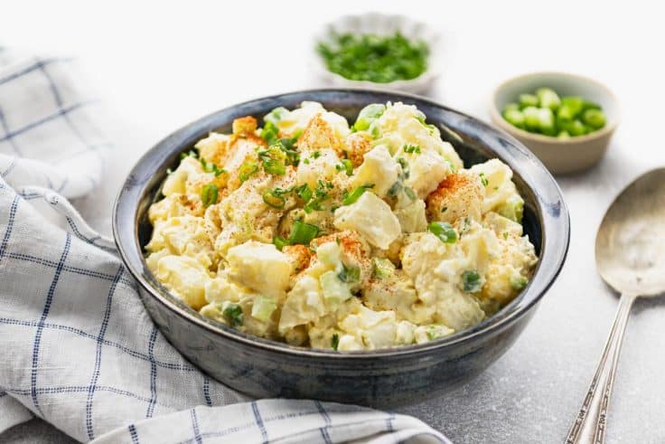 Horizontal image of southern potato salad on a white surface.
