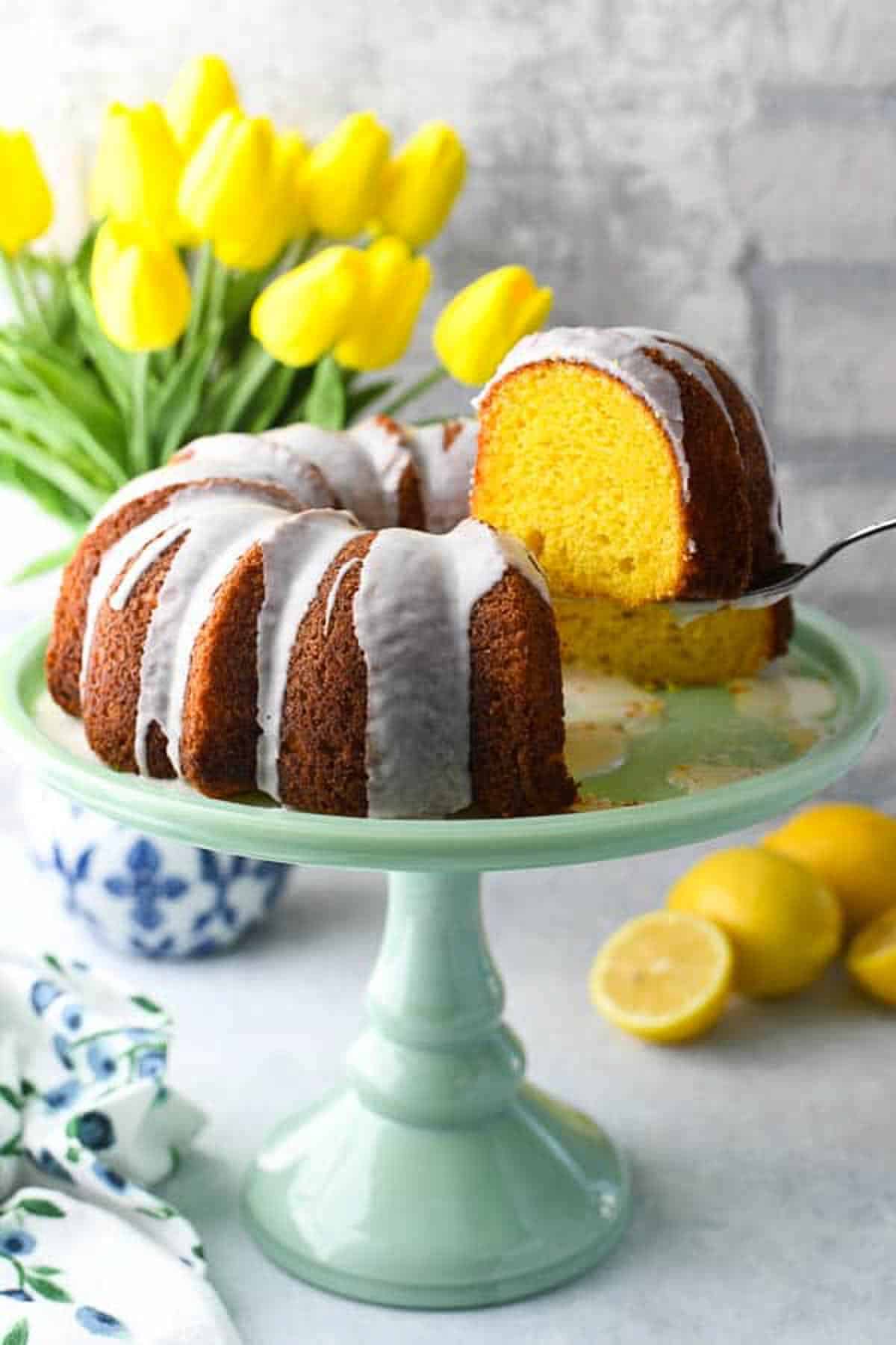 Front shot of a lemon bundt cake with tulips as part of a collection of easy spring desserts.
