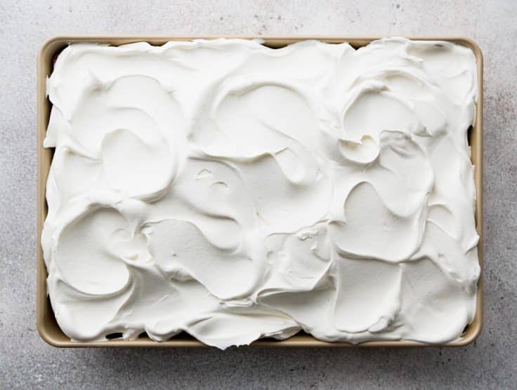 Spreading whipped cream on top of cake.