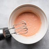 Mixing strawberry cake batter with electric hand mixer.