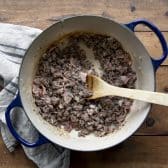 Browning ground beef, bacon, and onion in a cast iron dutch oven.