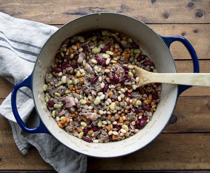 Process shot showing how to make grandma's cowboy calico beans recipe in a dutch oven.