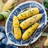 Horizontal overhead shot of corn on the cob in the oven and served on a blue and white plate.