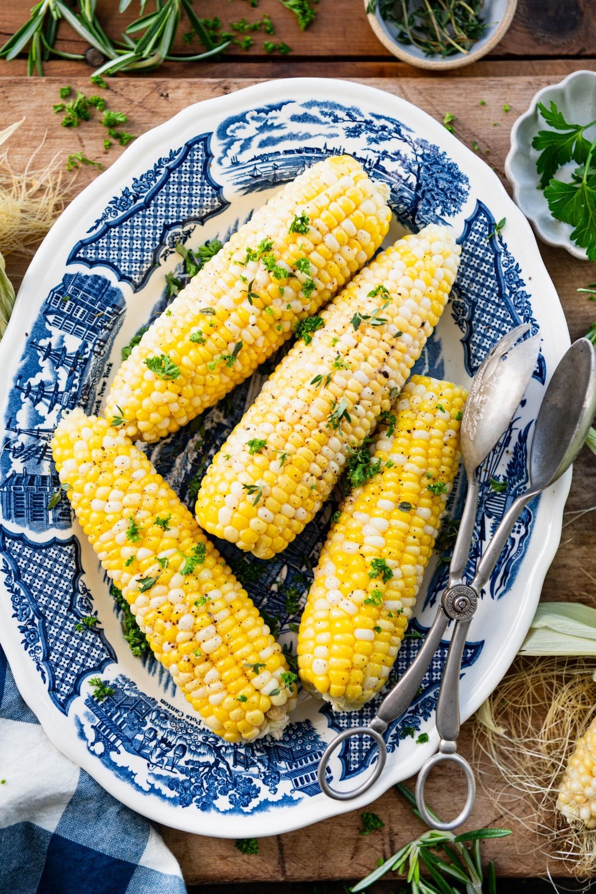 Platter of corn on the cob with butter, salt, pepper, garlic, and herbs.