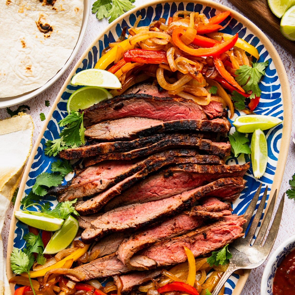 Square overhead shot of a platter of flank steak fajitas.
