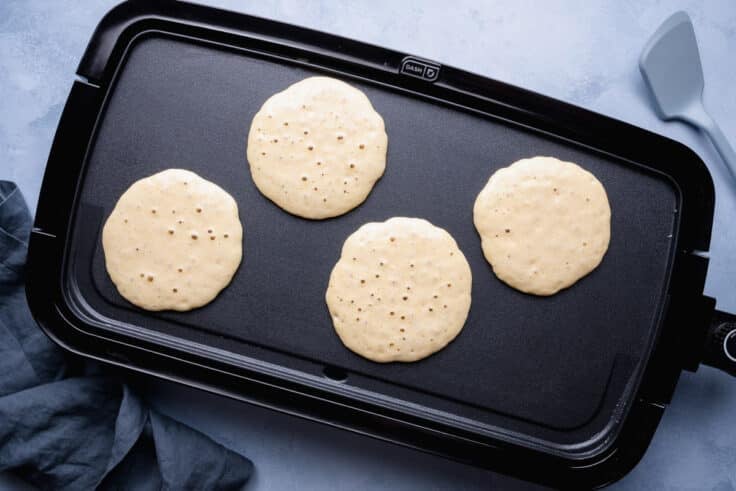 Overhead shot of cornbread pancakes on a griddle.