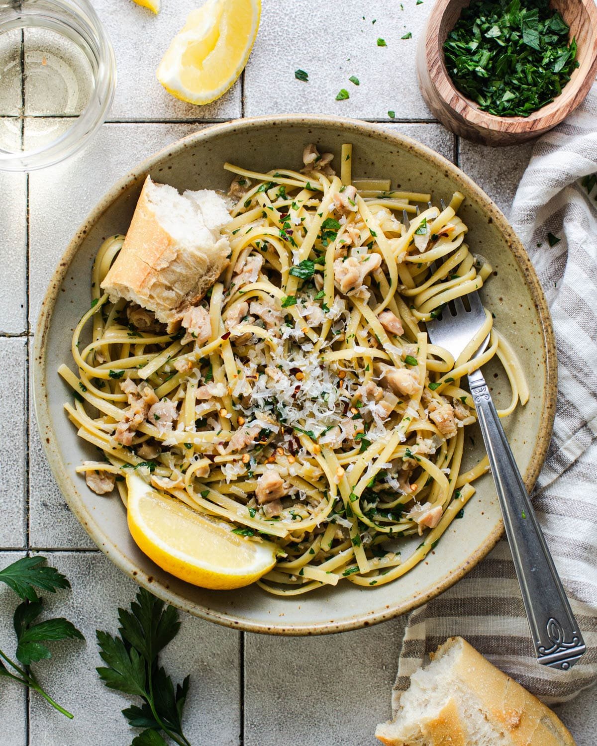 Overhead shot of a bowl of linguine with clam sauce garnished with lemon and fresh parsley.