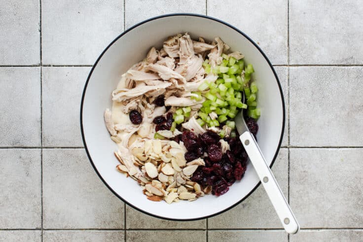 Chicken, veggies, fruit, and nuts in a large bowl.
