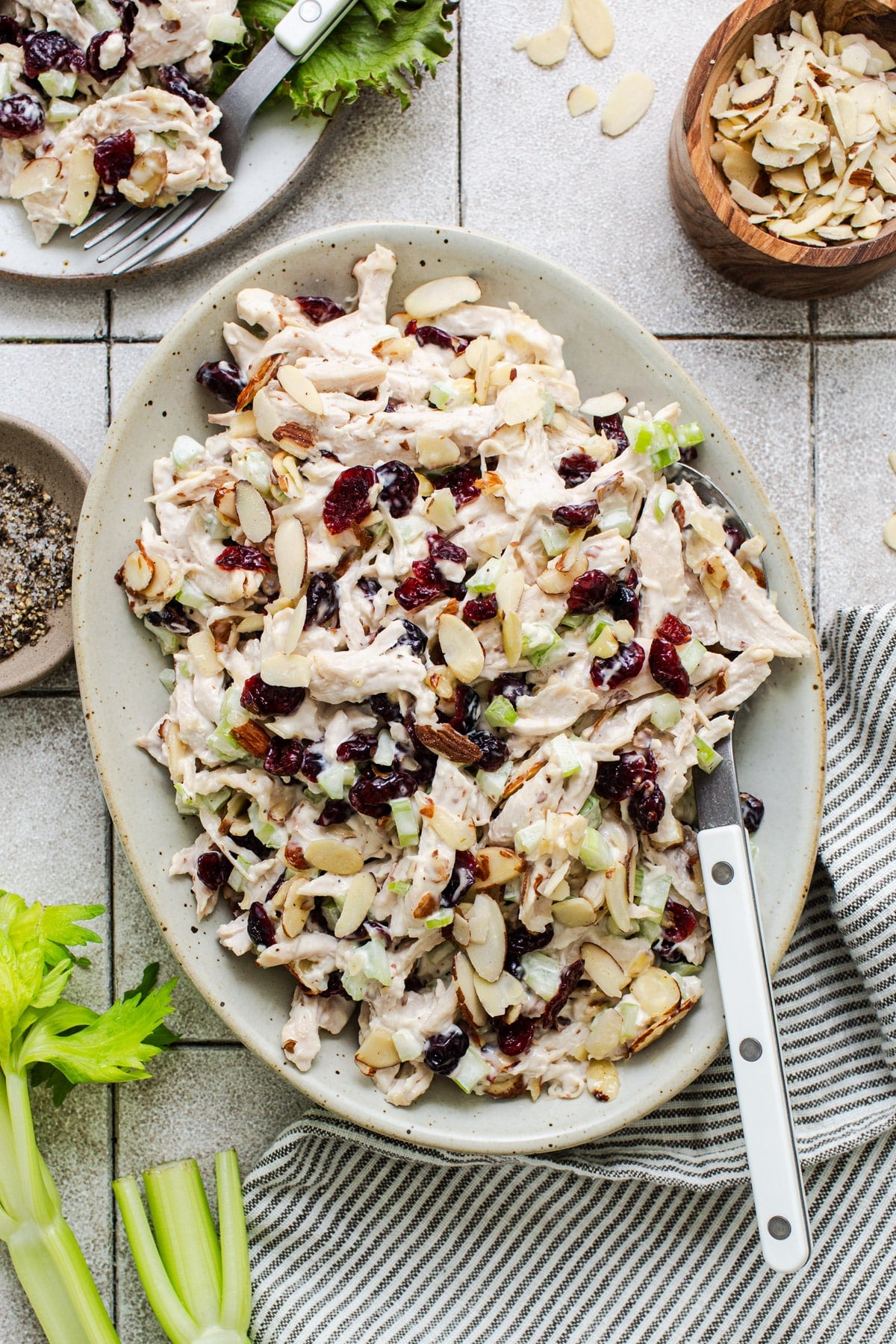 A sweet chicken salad recipe in a serving bowl on a white tile table.