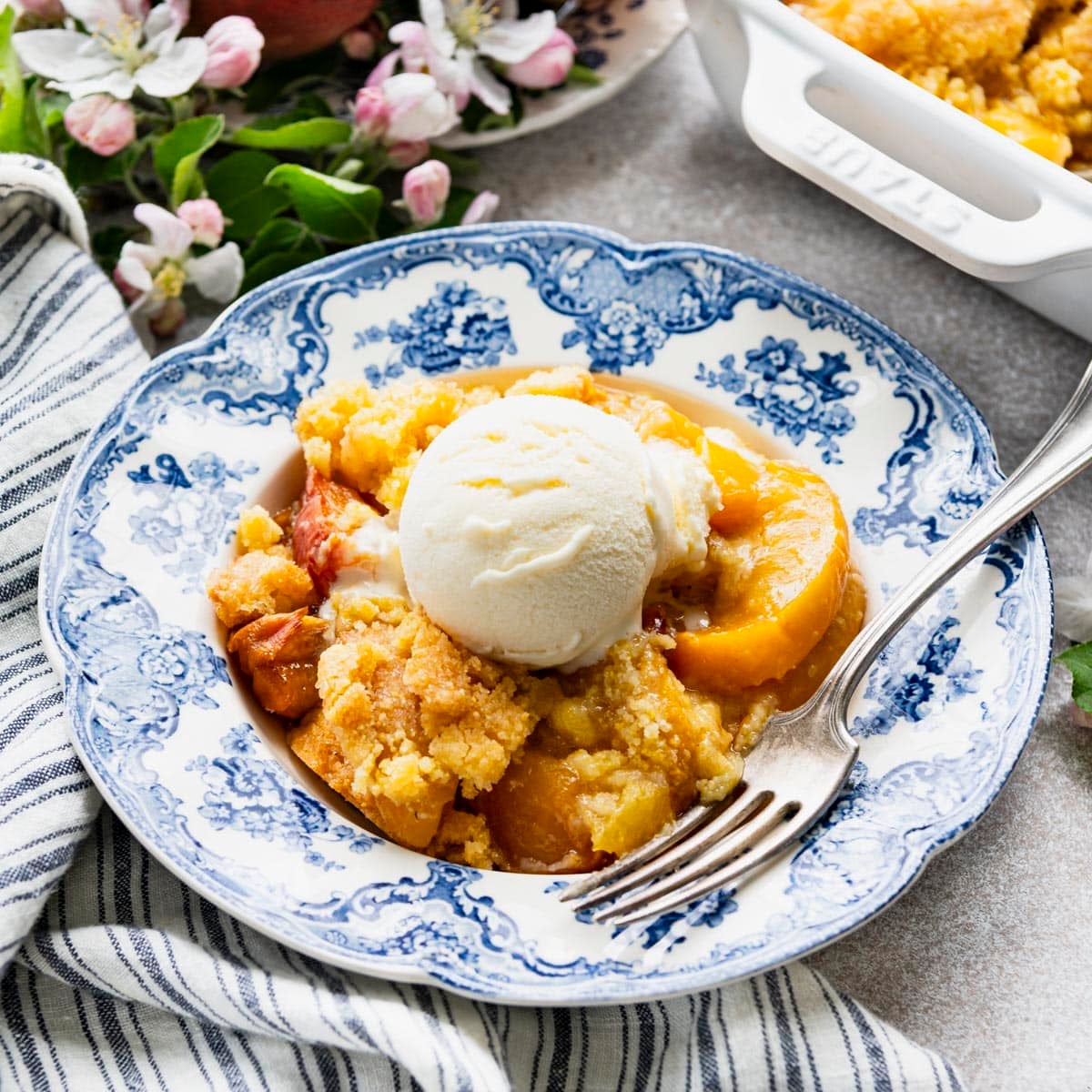Square side shot of southern peach cobbler with jiffy mix in a blue and white bowl.