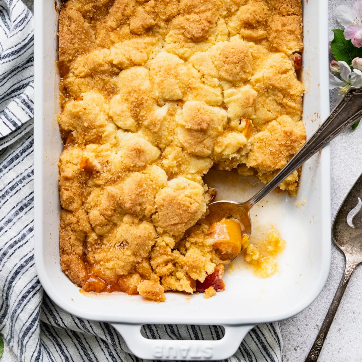 Square overhead shot of old fashioned peach cobbler in a white baking dish.