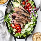 Square overhead shot of a steak salad recipe served in a cast iron dish with homemade balsamic vinaigrette.