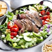 Horizontal side shot of steak salad on a white table.
