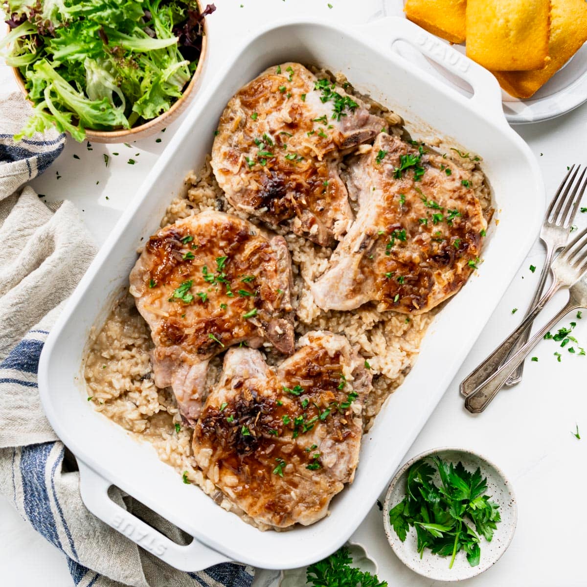 Square overhead shot of baked pork chops and rice in a white casserole dish.