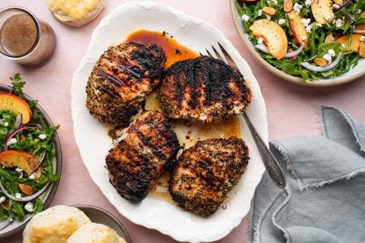 Horizontal overhead shot of grilled pork chops on a white serving platter.