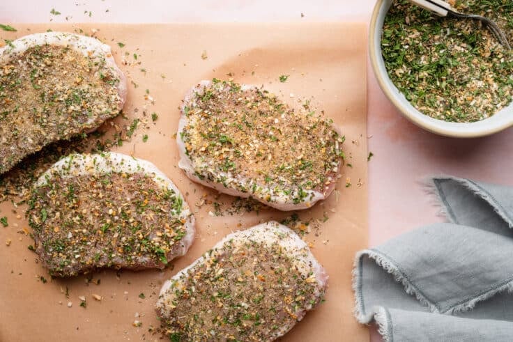 Seasoning the pork chops.