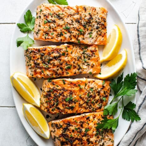 Square overhead shot of a platter of grilled salmon.