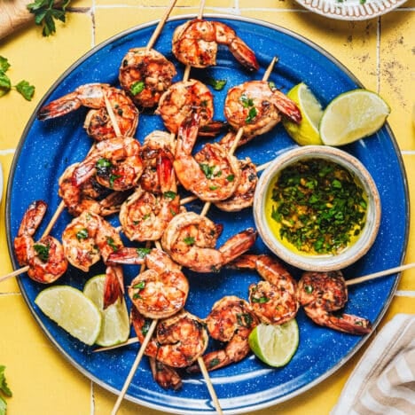 Square overhead shot of marinated grilled shrimp on a blue serving platter.