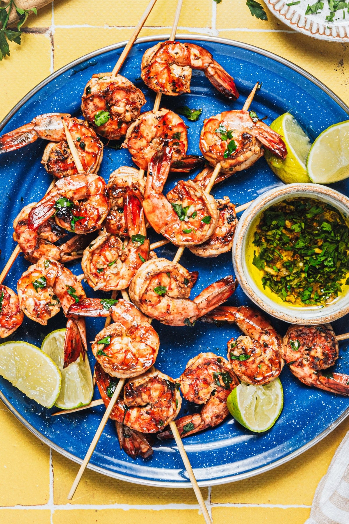 Overhead shot of marinated grilled shrimp on a blue serving platter.