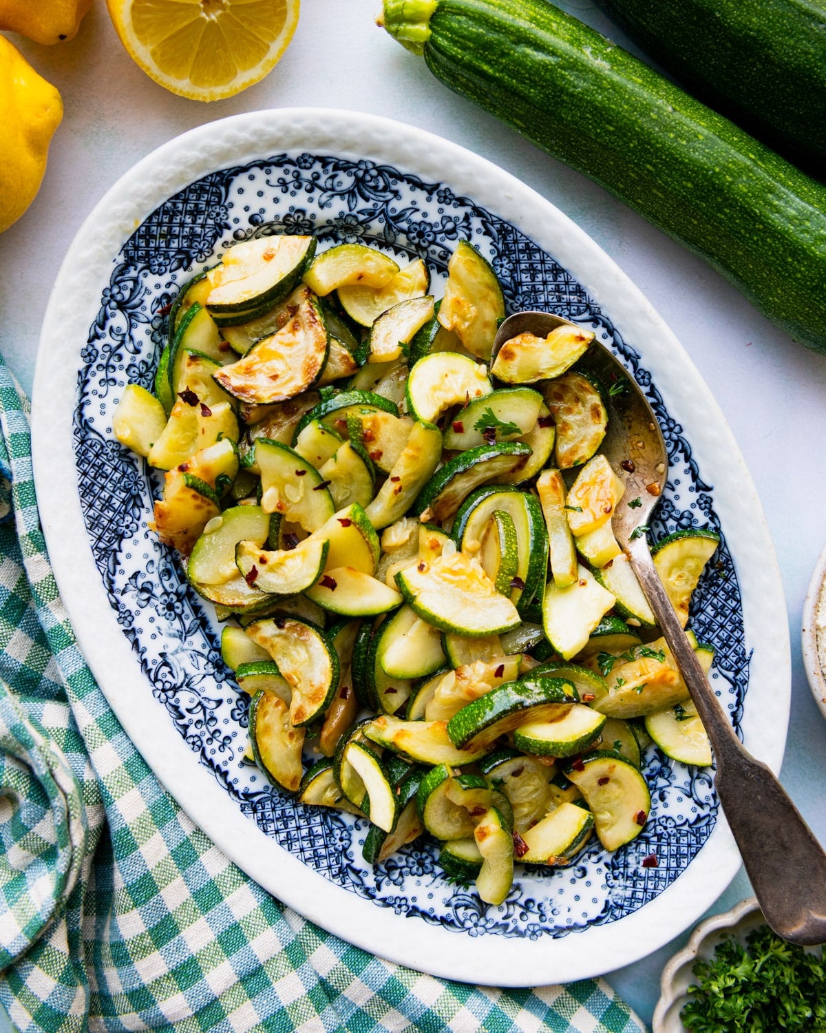 Overhead shot of sauteed zucchini on a blue and white serving platter.