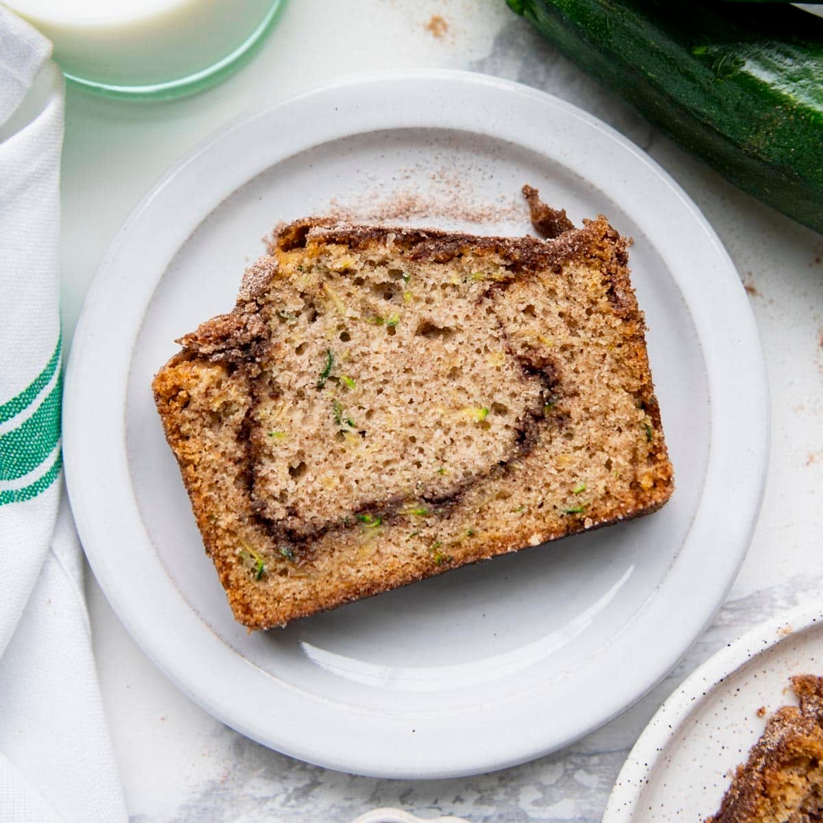 Square overhead shot of a slice of snickerdoodle zucchini bread on a white plate.