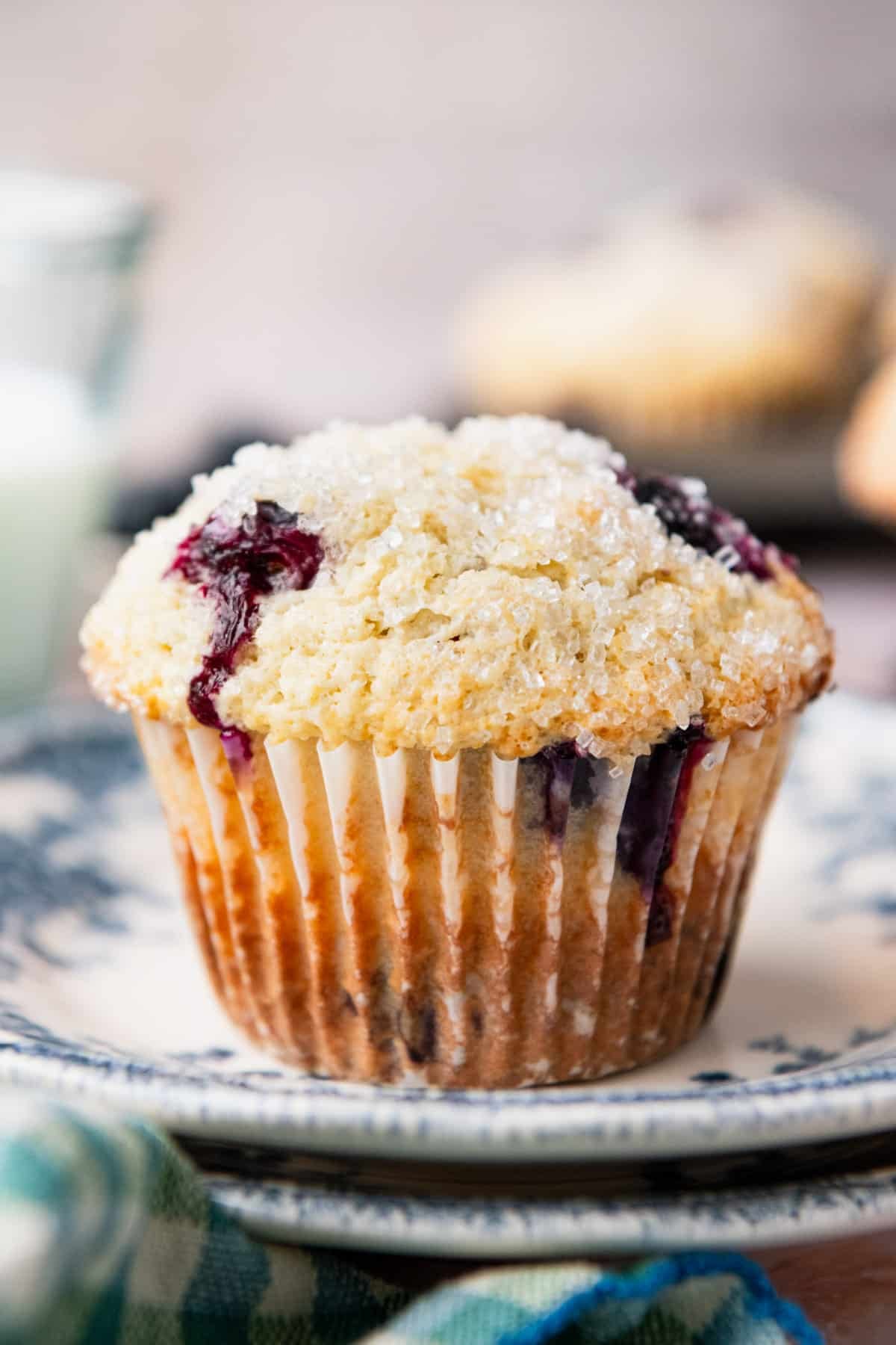 Close up side shot of a sour cream blueberry muffin on a blue and white plate.