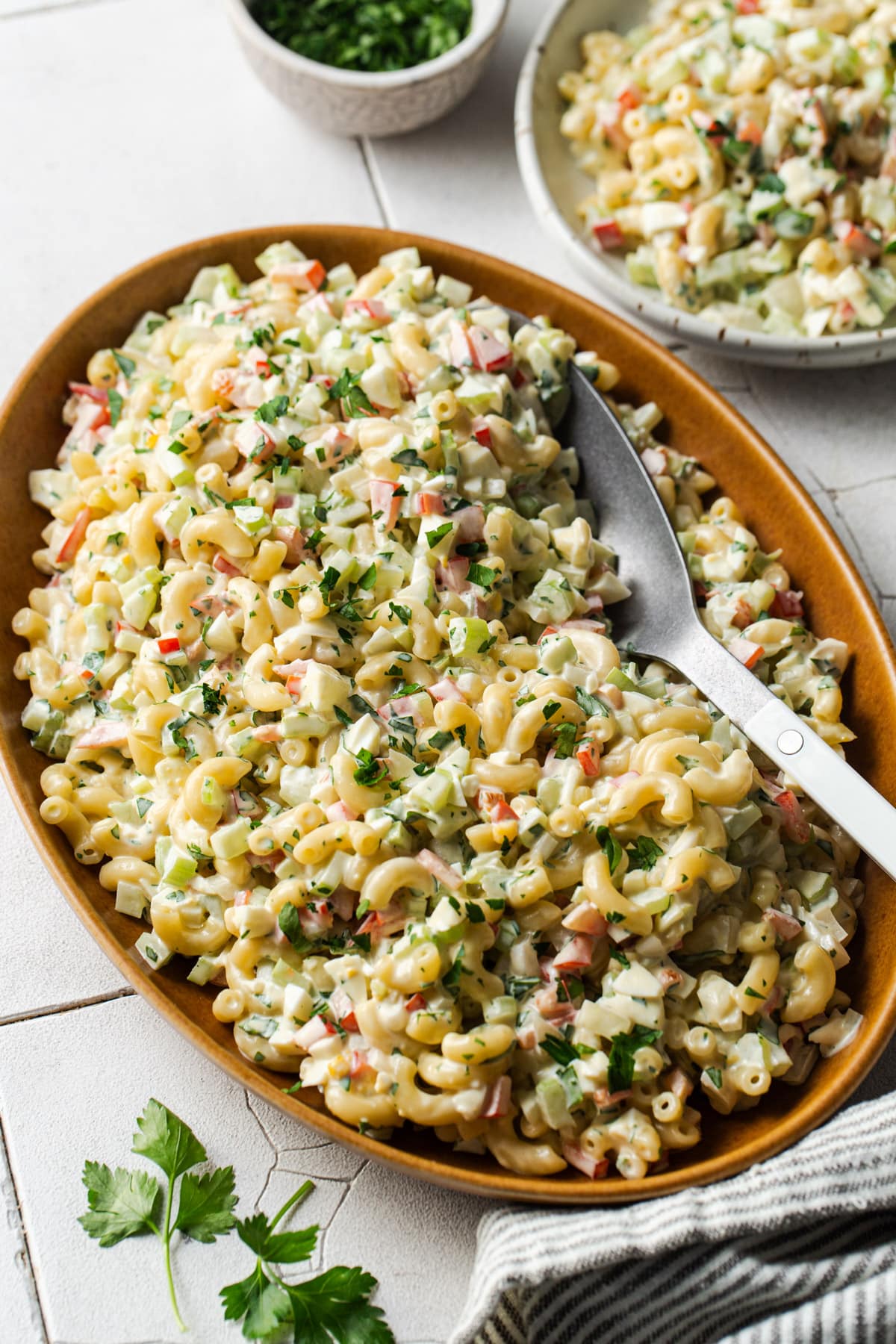 Overhead shot of a serving spoon in a wooden bowl of Southern macaroni salad.