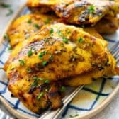 Close up square side shot of a platter of grilled golden turmeric chicken.