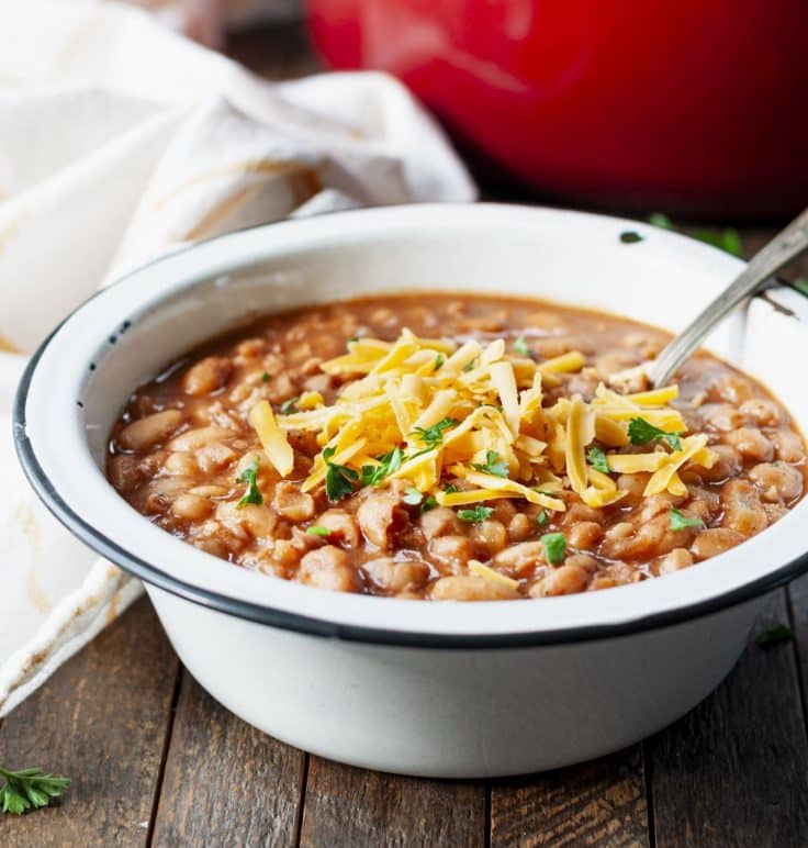 Side shot of a bowl of ranch-style pinto beans on a wooden table.