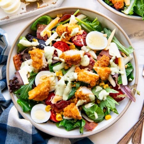 Square overhead shot of a chick fil a cobb salad recipe in a bowl on a white table.