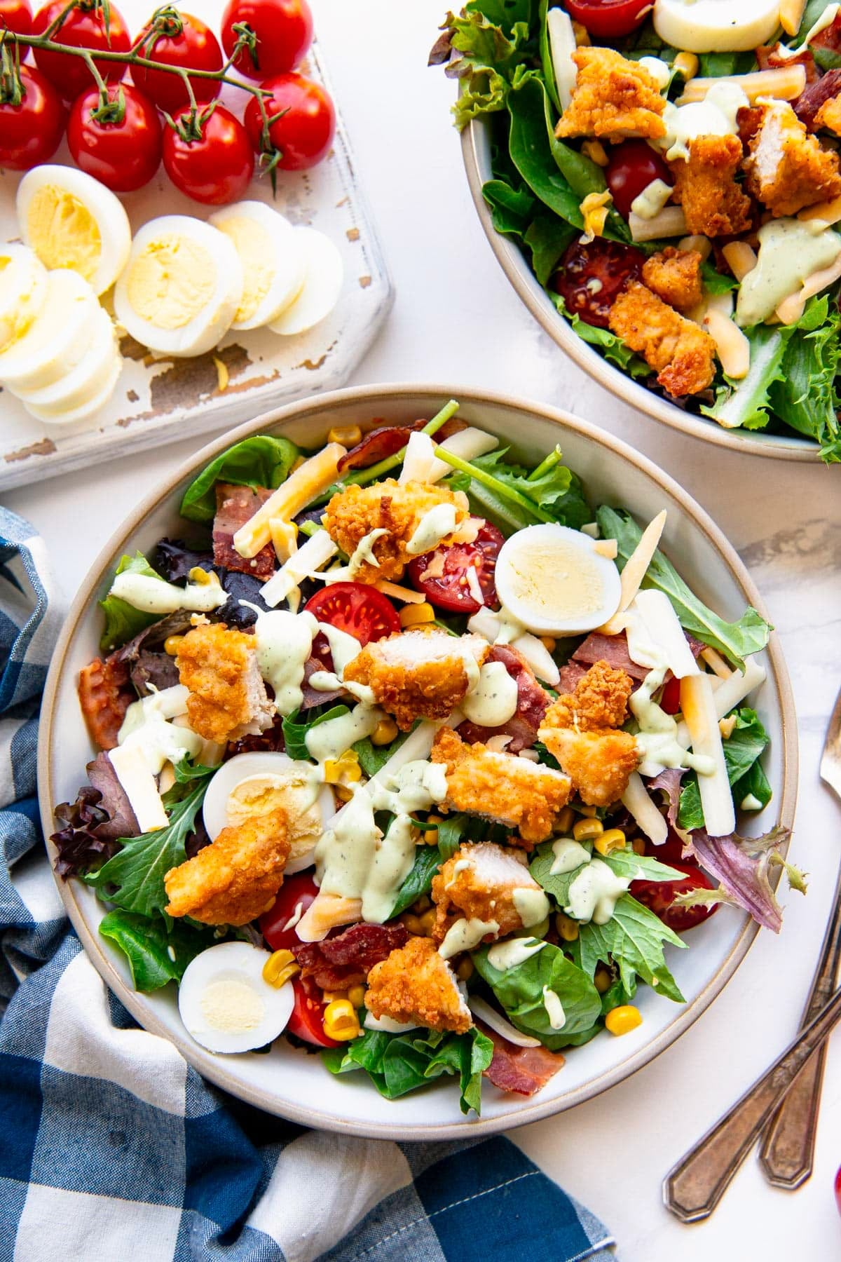 Overhead shot of two bowls of chick fil a cobb salad on a white table.